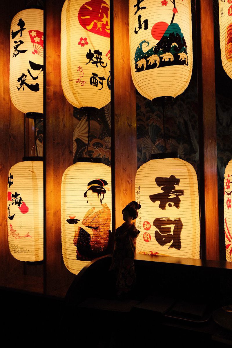 Paper lanterns with Japanese characters and a geisha figure at Umi Sake Haus